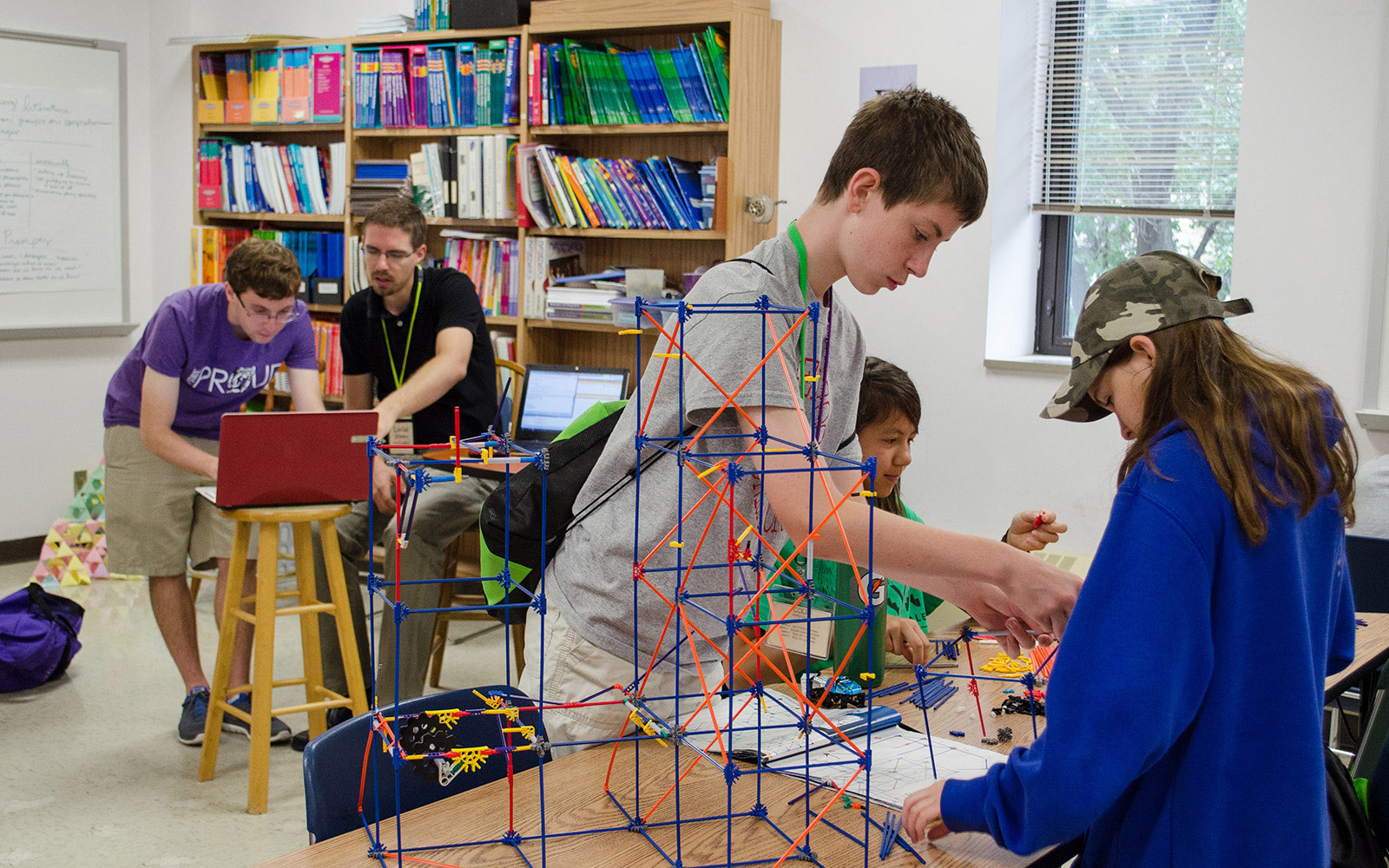 male college student, male K-12 teacher and middle school students create small-scale roller coasters in a STEM Institute